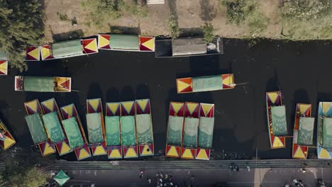 Toma-Cenital-De-Barcos-Navegando-En-Un-Río-Tranquilo,-Xochimilco,-Ciudad-De-México