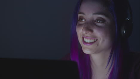 Close-up-of-Young-girl-smiling-while-she-uses-her-laptop-and-listens-music-on-her-headphones