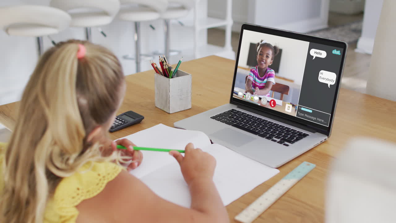 Schoolgirl using laptop for online lesson at home, with diverse schoolgirl and webchat on screen