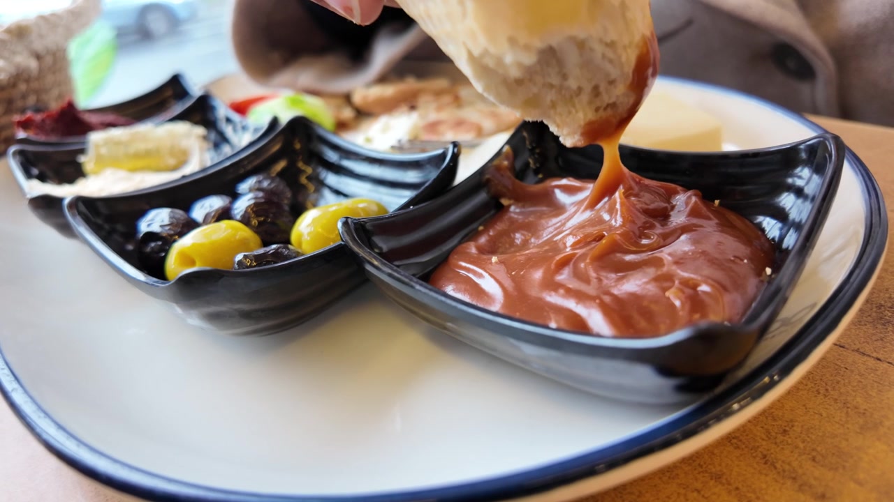 Dipping Fresh Bread into Chocolate Spread at Breakfast