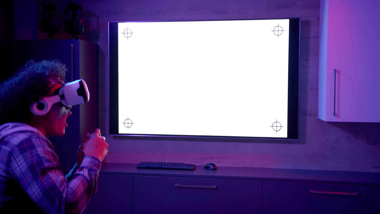 Using VR headset, man playing video game in front of large screen at home, copy space