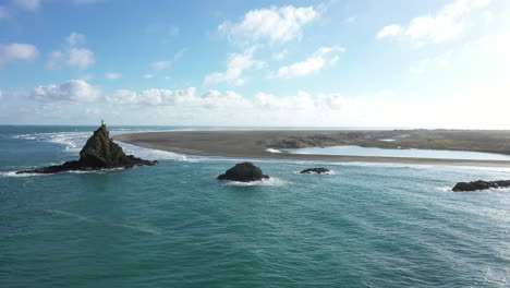 scenic panorama of lighthouse rock by huia beach, huia reserve, new zealand