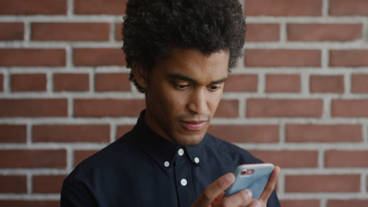 ritratto giovane uomo di razza mista che usa uno smartphone, naviga messaggi online, legge messaggi sul cellulare, sembra concentrato, si concentra al rallentatore