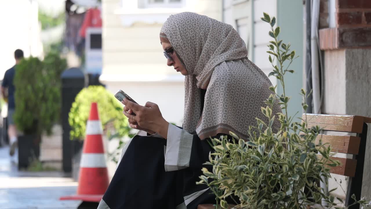 Woman in hijab using a mobile phone on a city street