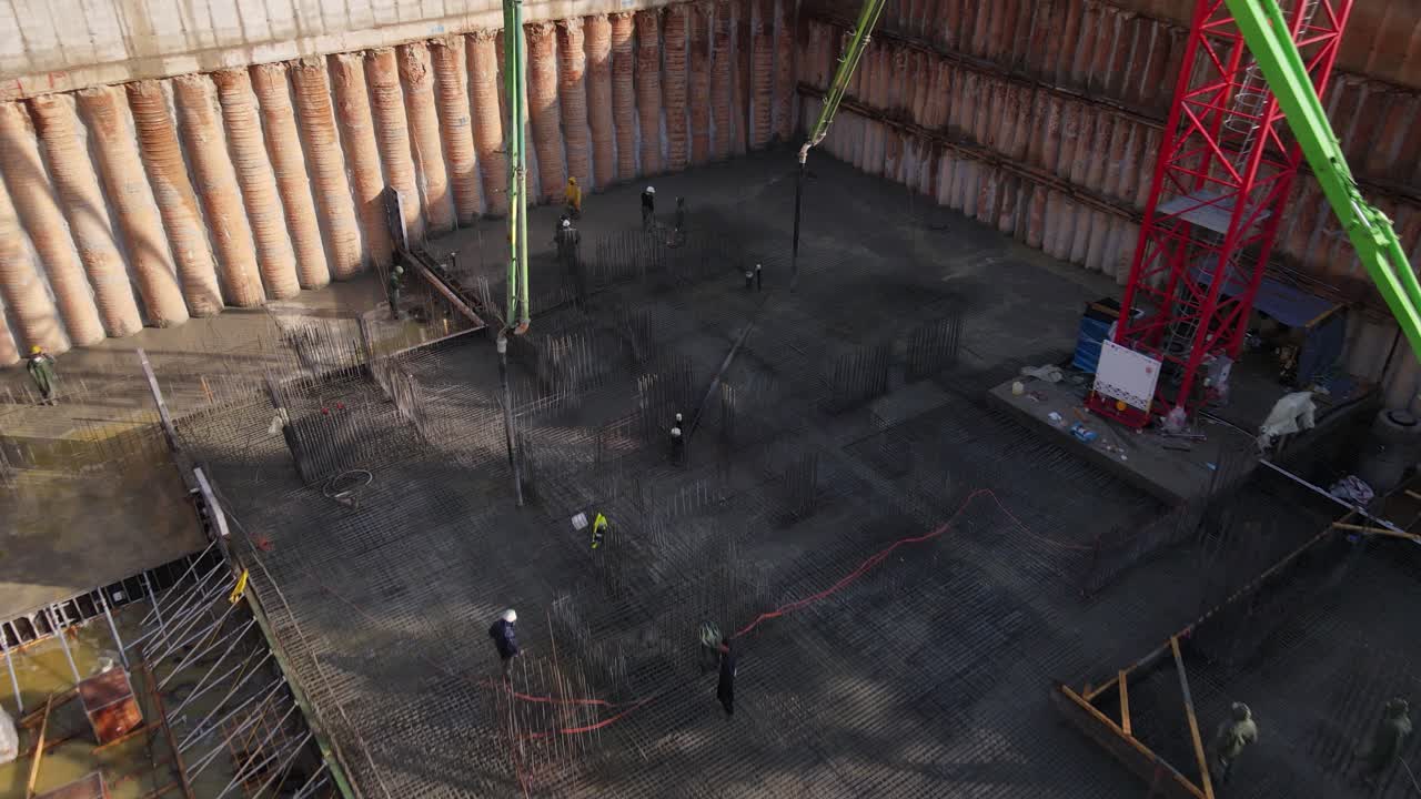 자동 펌프를 사용하여 젖은 시멘트를 깔고 있는 건설 노동자들의 조감도