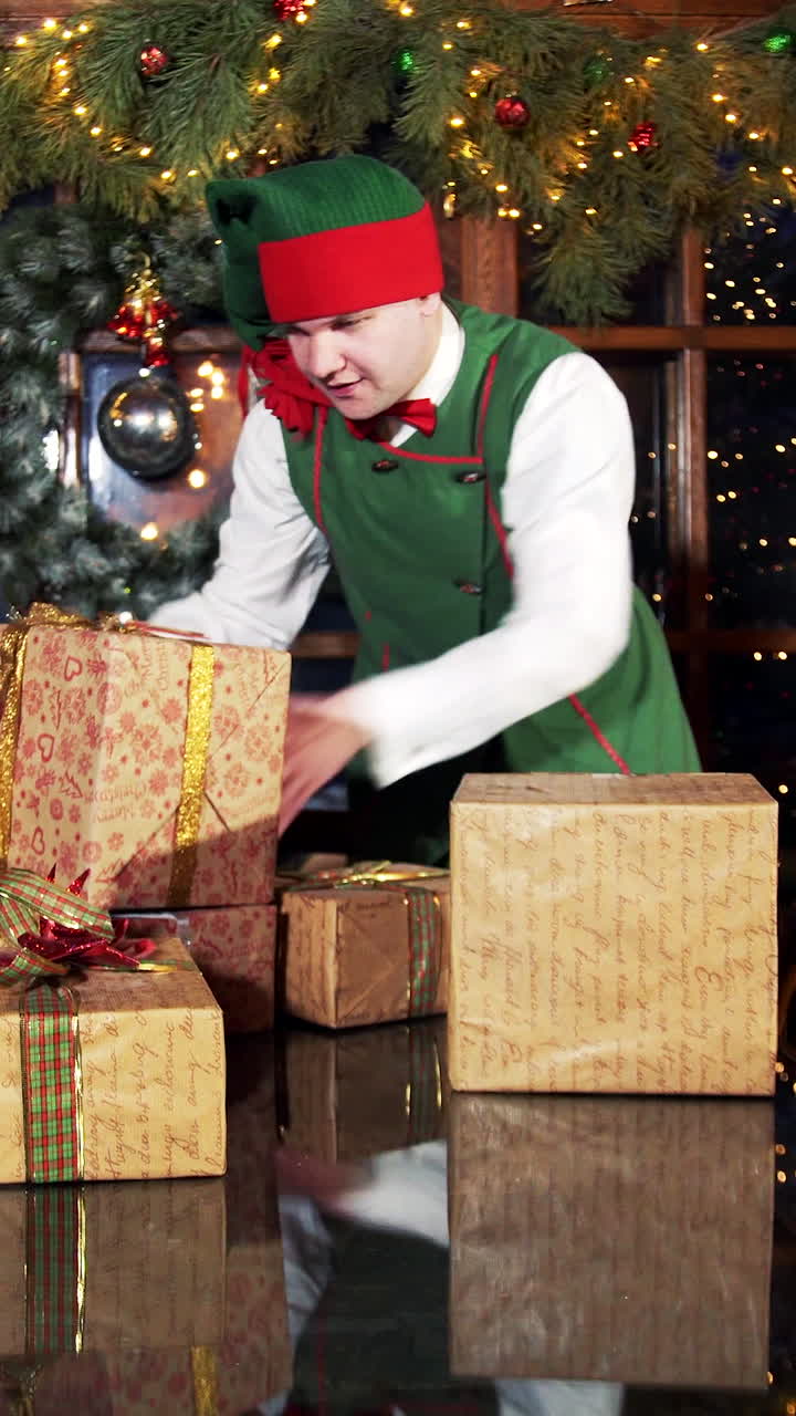 Happy boy working with Christmas presents. Elves put gift boxes on the table in the Christmas decorated room in Santa's residence. Vertical video