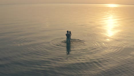 the man and woman holding hands and spin in circle against the beautiful sunset