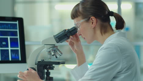 female scientist using microscope and tablet in laboratory