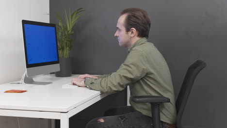 hombre en una camisa que trabaja en una oficina, escribiendo en la computadora, pantalla verde