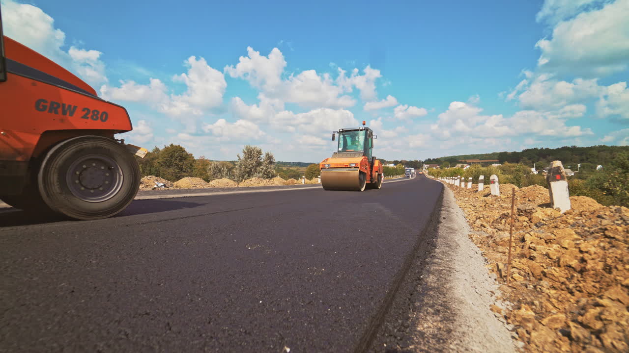 workers carry out construction and repair works of roads with the help of professional equipment near the city in the summer. Close-up