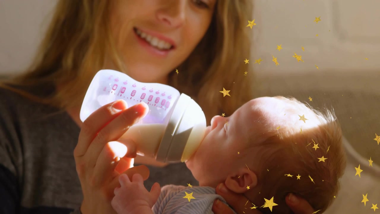 Vidéo verticale : Maman tenant un bébé, commençant à le nourrir au biberon pour sa santé, étoiles dérivant autour