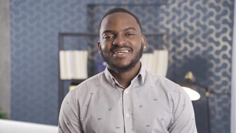 African-employee-looking-at-camera-and-laughing.-He's-in-his-office.