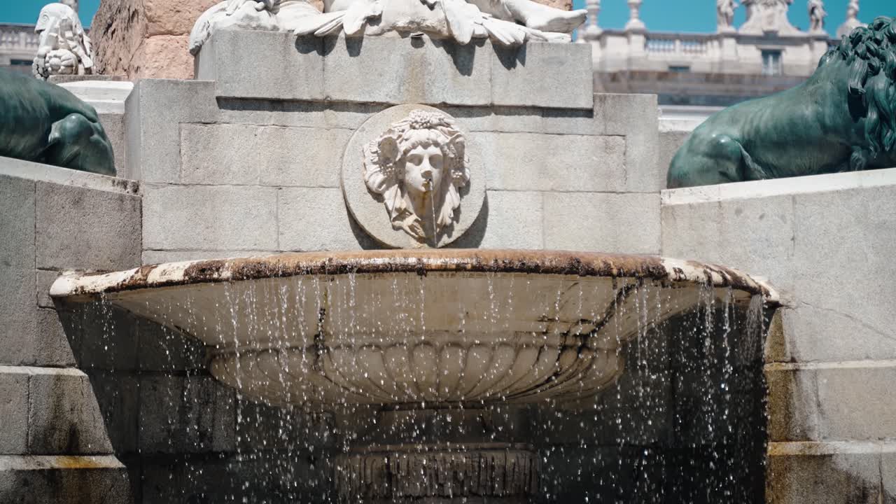 Water falls over carved stone tiers of a historic fountain in Madrid Spain