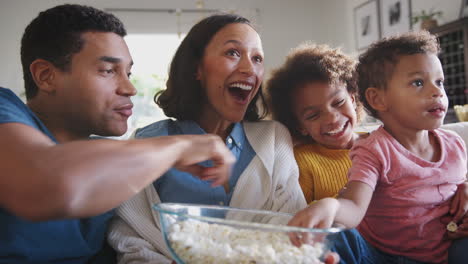 Joven-Familia-Afroamericana-Sentada-En-El-Sofá-Viendo-Televisión-Y-Comiendo-Palomitas-De-Maíz,-ángulo-Bajo,-Primer-Plano