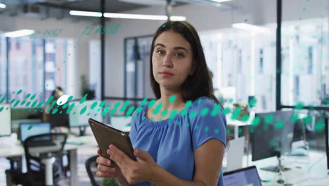 animación del procesamiento de datos financieros sobre una mujer de negocios biracial que usa una tableta en la oficina