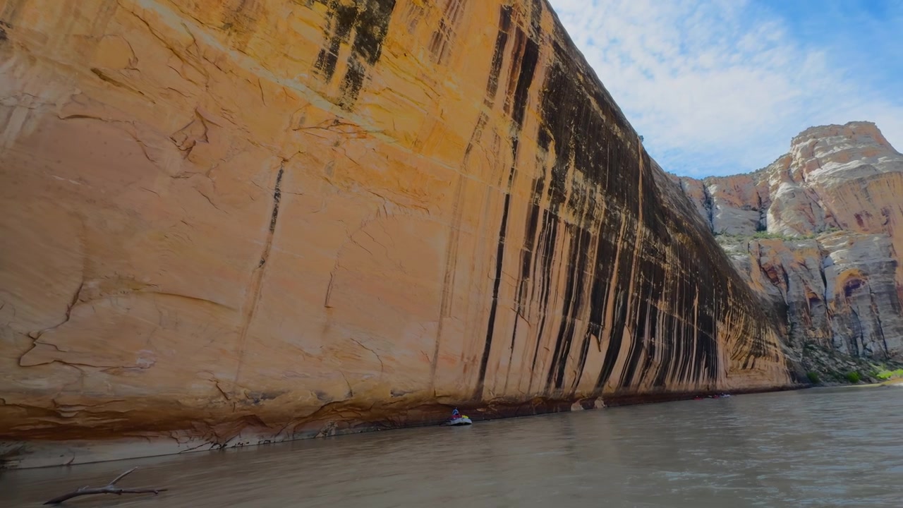 Parete ripida del canyon che si erge direttamente dalle acque del fiume in una spettacolare gola di arenaria, con striature scure nere che gocciolano