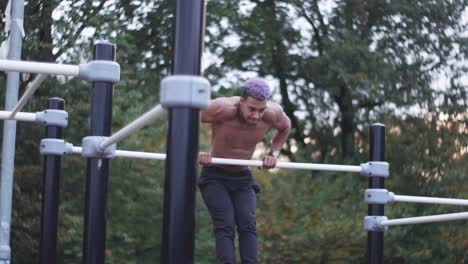 dolly shot of a young ripped man doing muscle ups in an outdoor calisthenics sports park