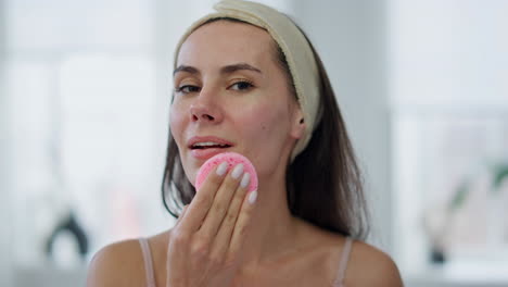 Smiling-woman-cleaning-face-looking-camera-pov-view.-Happy-girl-using-sponge