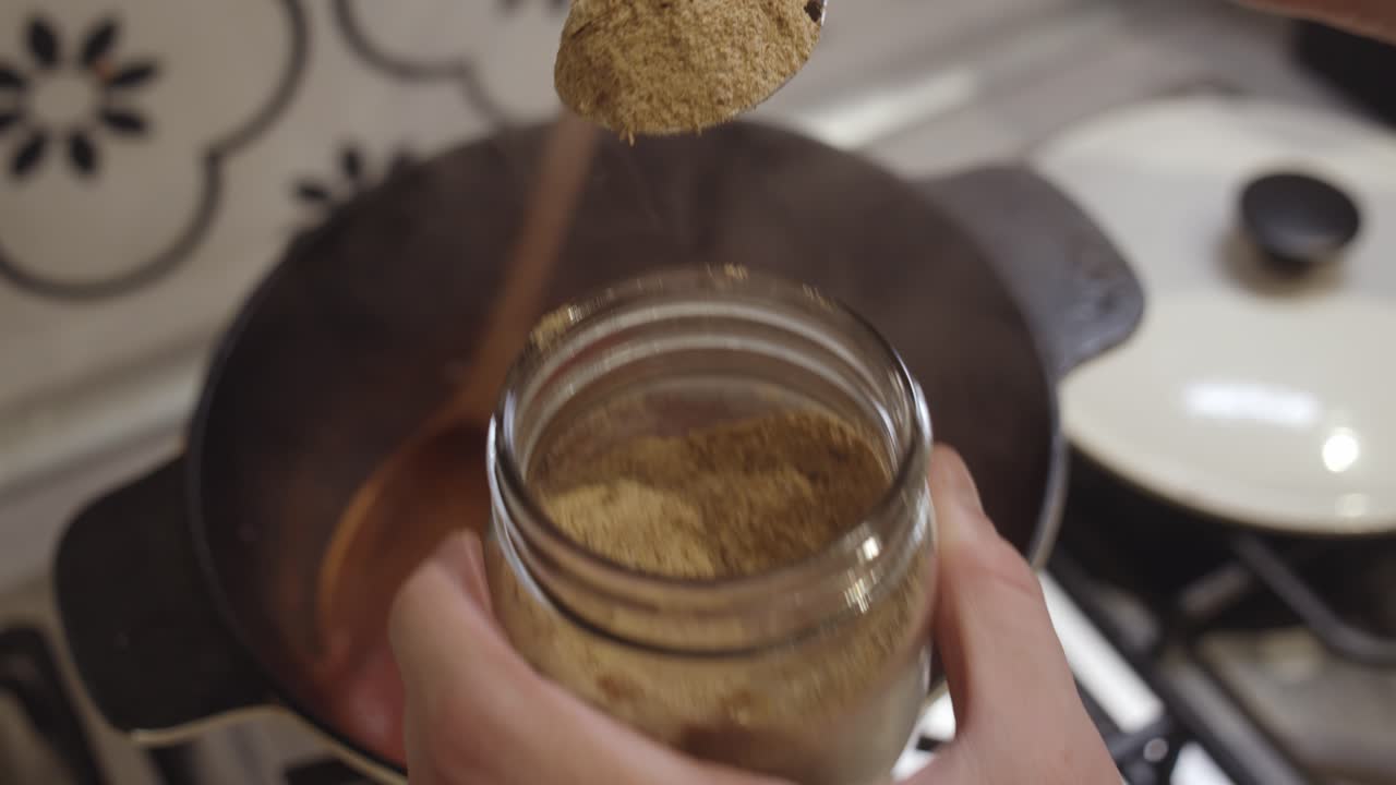 добавление индийской приправы бирияни в горячую кастрюлю для коксования на газовой плите