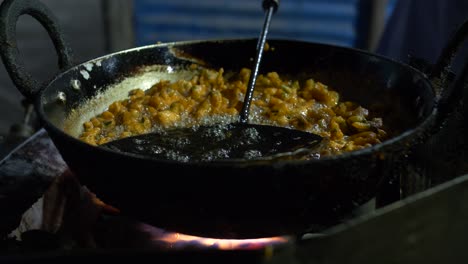 comida frita en aceite caliente en un mercado nocturno en una gran sartén de hierro