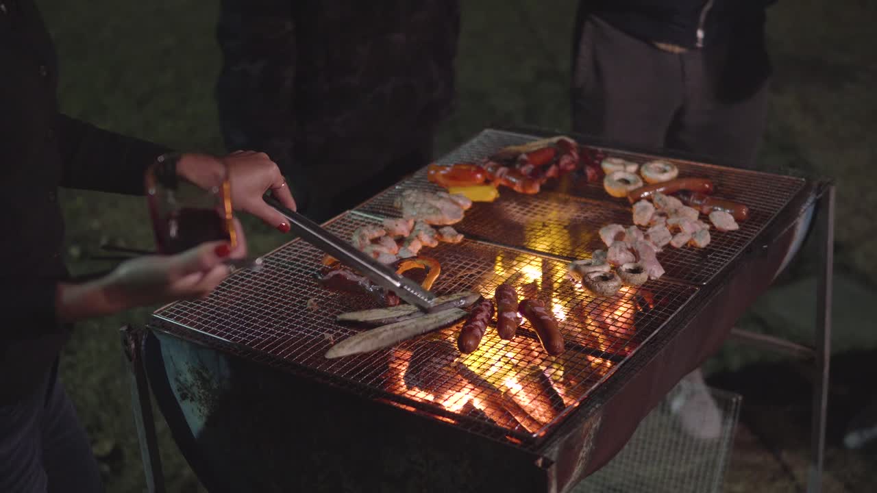 gente parada frente a la barbacoa y asando champiñones, salchichas, pollo, berenjena frente a la casa en un jardín