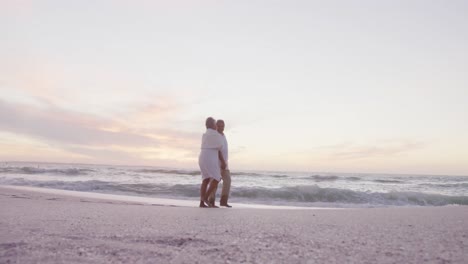 Glückliches-Hispanisches-Seniorenpaar,-Das-Bei-Sonnenuntergang-Am-Strand-Spaziert