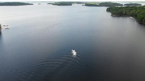 Drone-Siguiendo-Un-Barco-En-Un-Lago-En-El-País-De-La-Cabaña