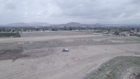 In-a-captivating-drone-shot,-a-water-truck-concludes-its-rotation-of-pouring-water-to-prepare-a-new-lot-for-home-construction