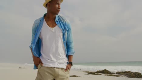 Front-view-of-African-american-man-walking-with-hands-in-pocket-on-the-beach-4k