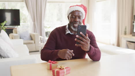 Feliz-Padre-E-Hijo-Afroamericanos-Con-Sombreros-Navideños-Teniendo-Videollamadas-Con-Teléfonos-Inteligentes,-Cámara-Lenta