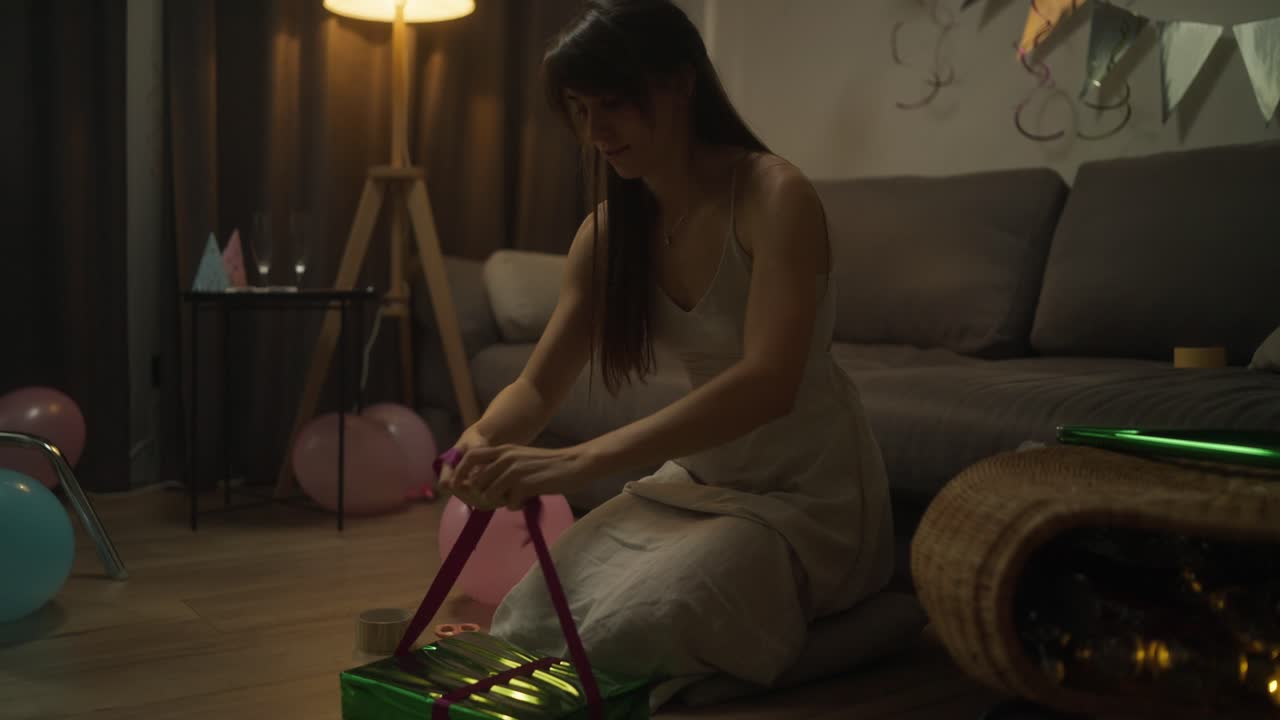 mujer abriendo un regalo en una fiesta por la noche