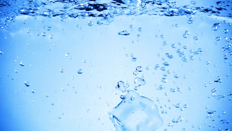 ice cubes dropped into water with air bubbles.