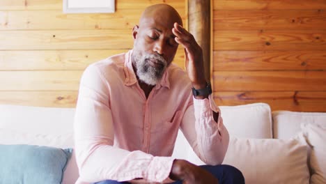 senior african american man spending time in log cabin and sitting on couch, slow motion