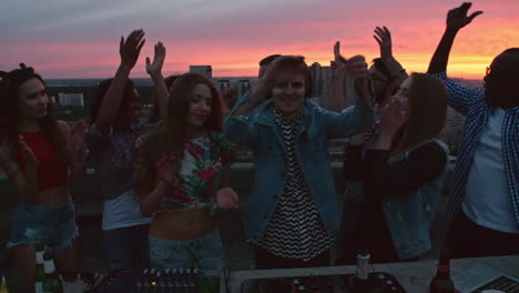 grupo de amigos disfrutando de una fiesta en una terraza al atardecer, todos animan al dj