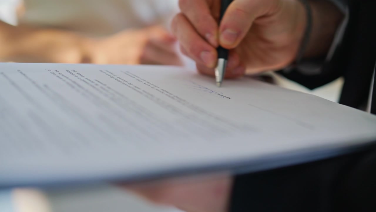 Closeup male hand signing contract with pen. Client putting signature on paper.