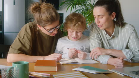kid studying at home with help of lesbian mothers