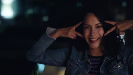 retrato de una hermosa mujer hispana haciendo caras en el techo por la noche divirtiéndose posando con expresiones tontas disfrutando de la vida nocturna urbana con luces de la ciudad bokeh en el fondo