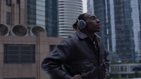 Black-man-in-urban-environment-puts-on-wireless-headphones-and-zones-out