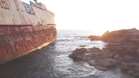 a dramatic aerial view of the edro iii shipwreck off the coast of cyprus, bathed in the warm hues of the setting sun