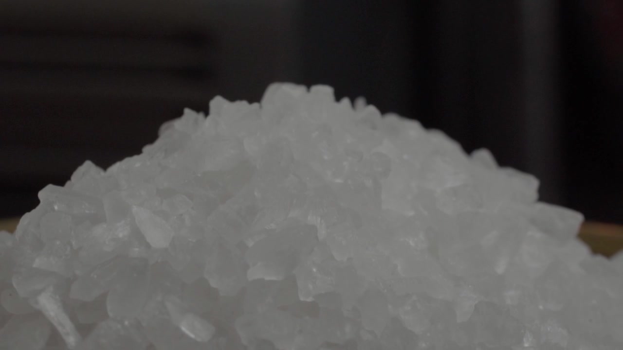 粗海盐晶体的微距特写，形成有质感的堆积，展示天然矿物结构和用于调味烹饪的食材。