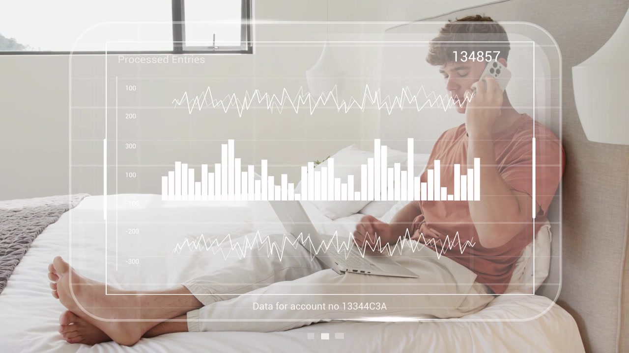 Man receiving call on phone and typing on laptop in bedroom, finance HUD showing account numbers
