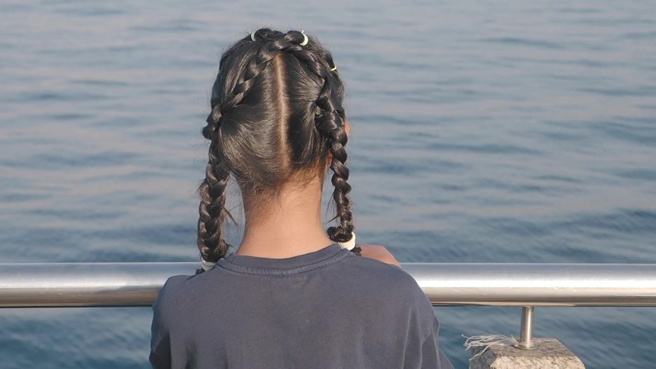 Giovane ragazza che guarda il mare da un molo