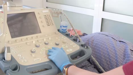close-up of the hands of an ultrasound doctor performing an ultrasound of the abdominal cavity on a patient with a modern scanner. modern medical diagnostic equipment. vertical video.