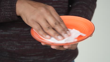 a man cleaning a plate with a paper towel