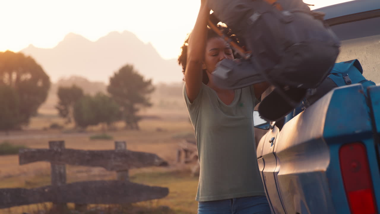 retrato de una mujer de pie al lado de una camioneta en un viaje por carretera a una cabaña en el campo