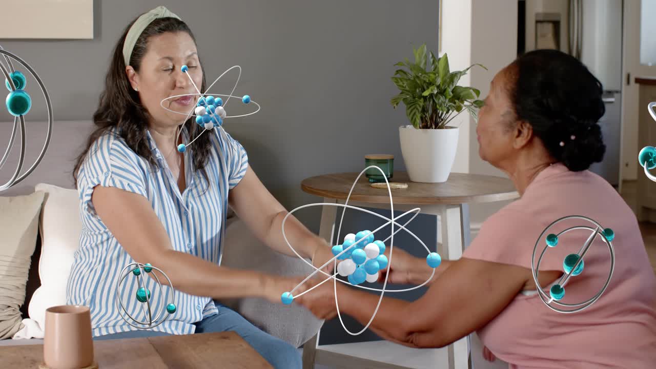 Mature woman reaching out, checking senior woman's wrist at home, atom overlay highlighting health