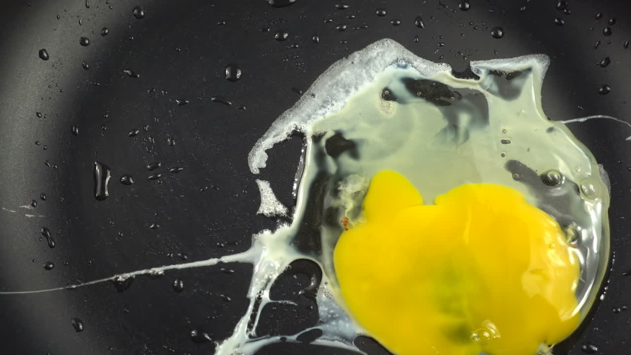 Preparation of fried eggs on a frying pan. Slow motion