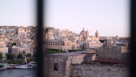 camera moves behind metal fence showing part of malta's famous three cities