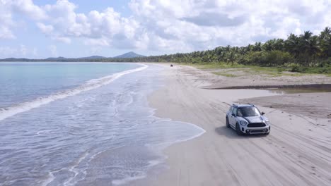 Mini-Cooper-Clásico-Conduciendo-En-La-Orilla-De-La-Playa