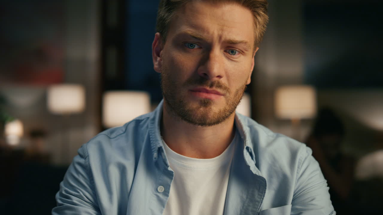 en primer plano un tipo serio terminando la llamada en el piso de la noche. hombre mirando a su esposa regocijándose